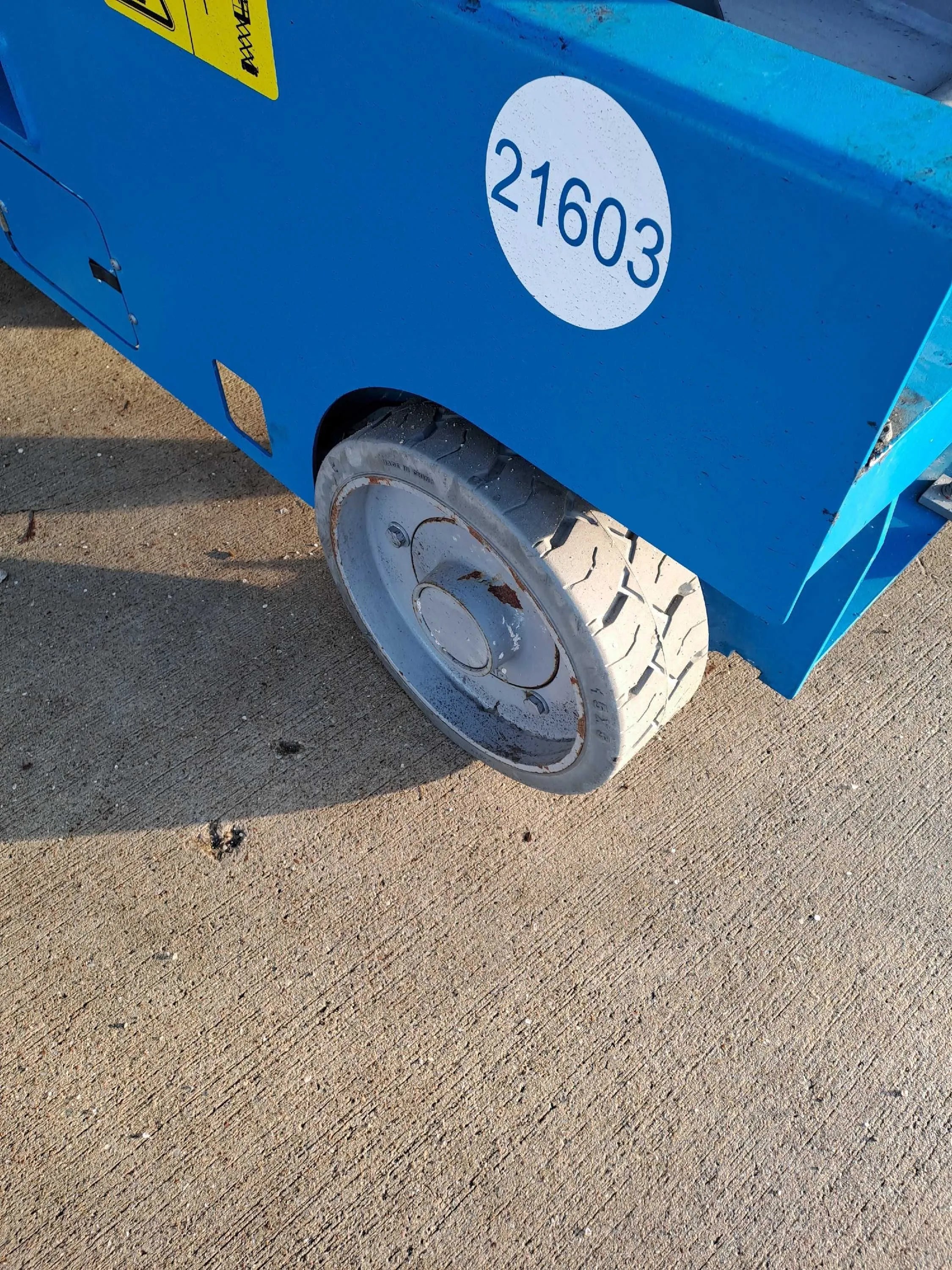 Blaue Arbeitsbühne mit Kennzeichen 21603 und robustem Reifen auf Baustelle